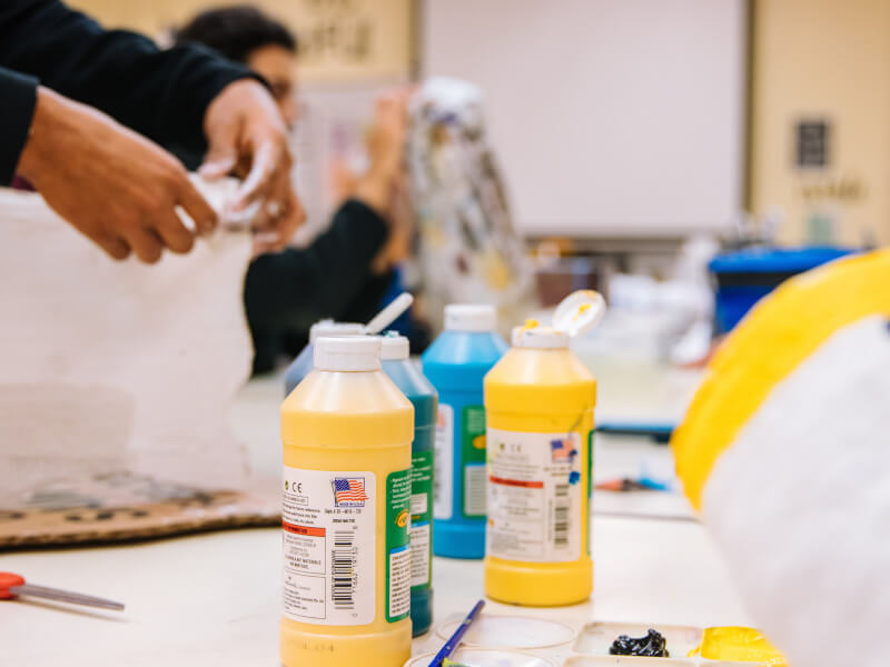 An art class with people working on paper with large bottles of paint